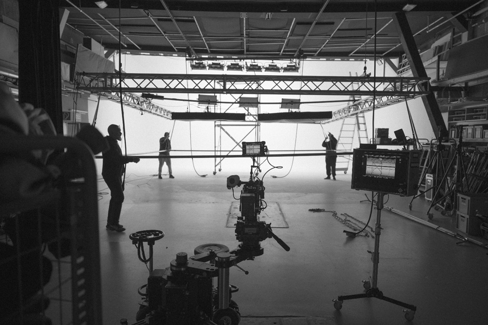 Filmstudio making of black-and-white crew setting up scene with truss